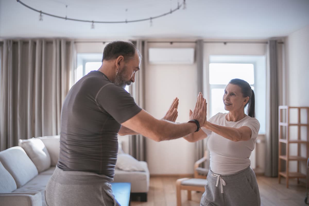 Two people working through a movement together in a bright living room.